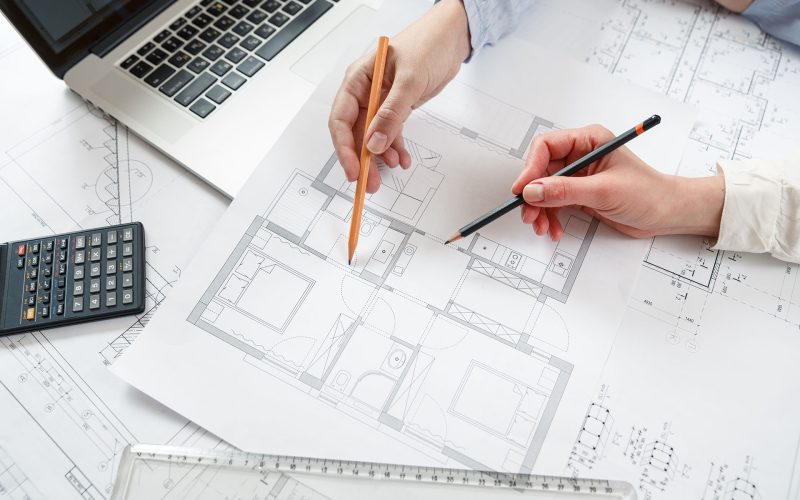 Young female architect and designer working on blueprint project of new apartments. Photo concept of work on technical drawings